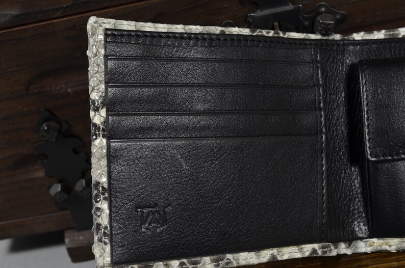 May include: A black leather wallet with multiple card slots and a billfold. The wallet is made of genuine snakeskin and has a subtle embossed logo on the front.