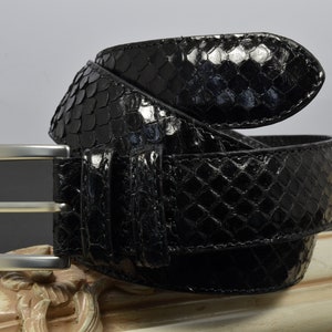 Pode incluir: Um cinto de couro preto com uma fivela de prata. O cinto é feito de pele de cobra e tem um padrão texturizado.