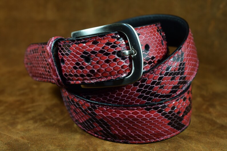 May include: A red and black snakeskin belt with a silver buckle. The belt is made of genuine leather and has a classic design.