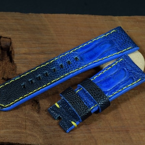 Op de afbeelding: Een blauw leren horlogebandje met gele stiksels. Het bandje heeft een gestructureerd oppervlak en is ontworpen voor een horloge met een lugbreedte van 22 mm.