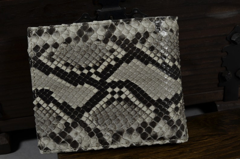 Pode incluir: Uma carteira de pele de cobra branca e preta com um padr&atilde;o de diamante.