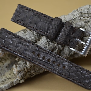 May include: A brown leather watch strap with a textured pattern. The strap has a silver buckle and is made of genuine alligator skin.