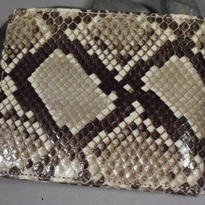 K&ouml;nnte beinhalten: Eine braune und wei&szlig;e Schlangenleder-Geldb&ouml;rse mit einem Rautenmuster. Die Geldb&ouml;rse ist aus echtem Leder gefertigt und hat eine glatte Oberfl&auml;che.