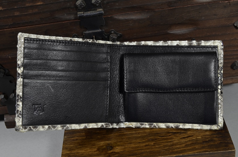 May include: A black leather wallet with multiple card slots and a billfold. The wallet is made of genuine snakeskin and has a subtle pattern.