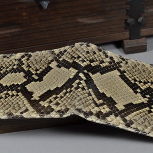 May include: A beige and brown snakeskin wallet with a textured pattern.