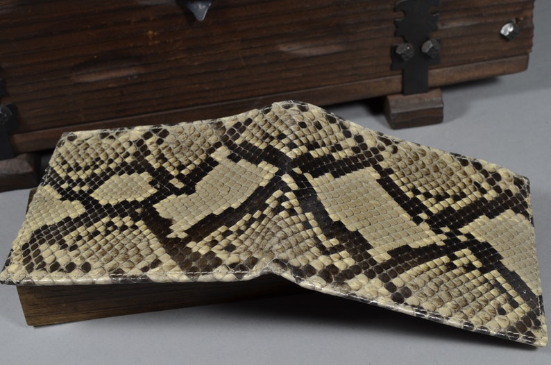 May include: A beige and brown snakeskin wallet with a textured pattern.
