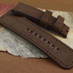 May include: A brown leather watch strap with stitching and multiple holes for adjusting the size.