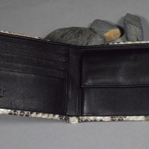 K&ouml;nnte beinhalten: Eine braune Lederb&ouml;rse mit Schlangenhautmuster. Die B&ouml;rse ist ge&ouml;ffnet und zeigt mehrere Kartenf&auml;cher und ein Geldfach.