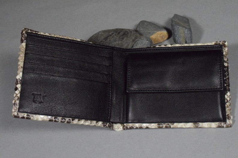 K&ouml;nnte beinhalten: Eine braune Lederb&ouml;rse mit Schlangenhautmuster. Die B&ouml;rse ist ge&ouml;ffnet und zeigt mehrere Kartenf&auml;cher und ein Geldfach.