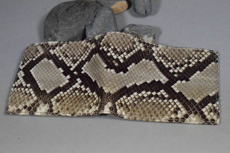 K&ouml;nnte beinhalten: Eine braune und beige Schlangenleder-Geldb&ouml;rse mit einer Klappverschluss.