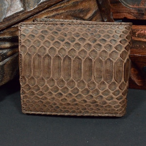 Op de afbeelding: Een bruine leren portemonnee met een slangenhuidpatroon.