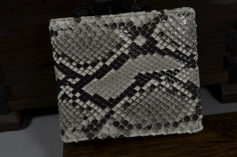 May include: A black and white snakeskin wallet with a diamond pattern. The wallet is made of genuine leather and has a smooth finish.
