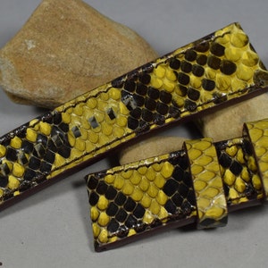 Peut inclure: Un bracelet de montre en cuir de serpent jaune et noir avec des coutures brunes. Le bracelet est en cuir véritable et possède une fermeture à boucle.