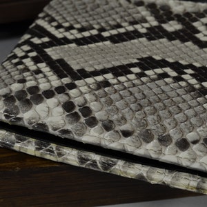 May include: A white and black snakeskin wallet with a textured surface.