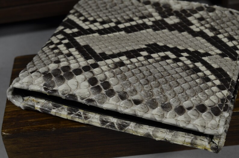 May include: A white and black snakeskin wallet with a textured surface.
