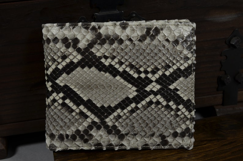 Pode incluir: Uma carteira de pele de cobra branca e preta com um padr&atilde;o de diamante.