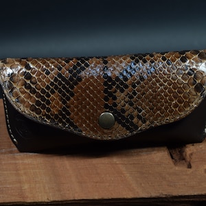 May include: A brown leather glasses case with a snakeskin pattern and a metal button closure.