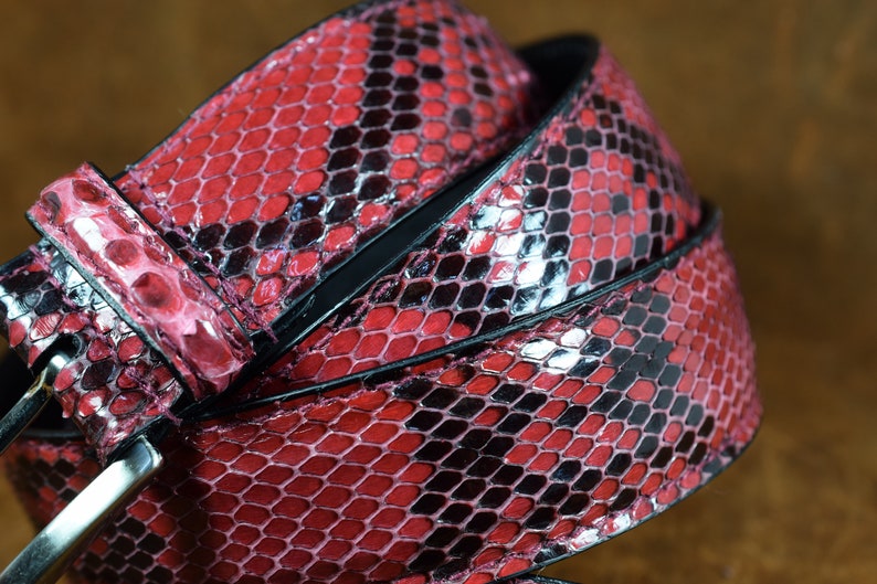 May include: A red and black snakeskin belt with a silver buckle.