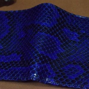 Peut inclure: Un portefeuille en cuir de serpent bleu avec un motif textur&eacute;.