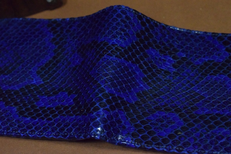 Peut inclure: Un portefeuille en cuir de serpent bleu avec un motif textur&eacute;.