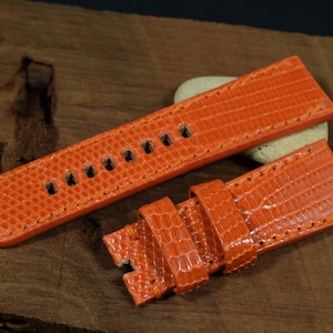 May include: Orange leather watch strap with a textured pattern. The strap is shown folded in half, with the stitching visible.