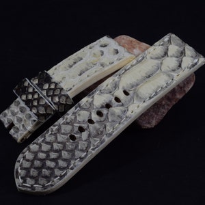 Może przedstawiać: Pasek do zegarka ze skóry węża w kolorze białym i szarym, ze szwami na krawędziach.