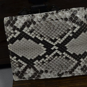 May include: A black and white snakeskin wallet with a diamond pattern. The wallet is made of genuine leather and has a smooth, textured finish.