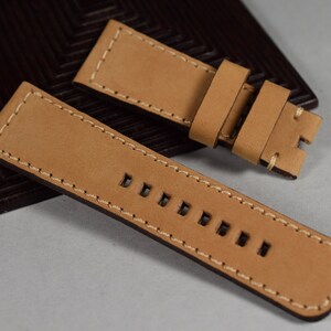May include: Two tan leather watch straps with white stitching. The straps have multiple holes for adjusting the size.