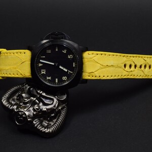 Op de afbeelding: Een zwart polshorloge met een gele leren band. De wijzerplaat van het horloge heeft Romeinse cijfers en een zwarte achtergrond.