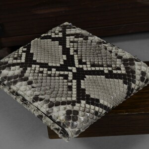 May include: A black and white snakeskin wallet with a textured pattern.