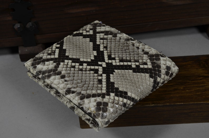 May include: A black and white snakeskin wallet with a textured pattern.