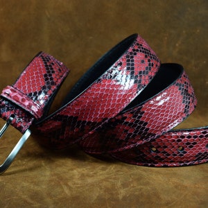 May include: A red and black snakeskin belt with a silver buckle.