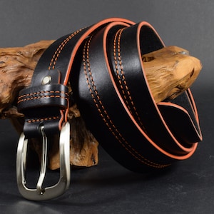 Könnte beinhalten: Ein schwarzer Ledergürtel mit orangefarbenen Nähten und einer silbernen Schnalle.