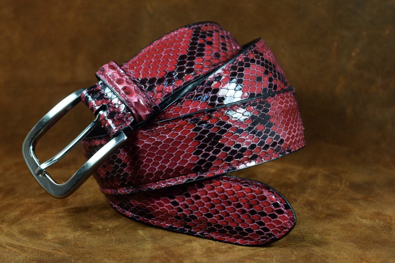 May include: A red and black snakeskin belt with a silver buckle.