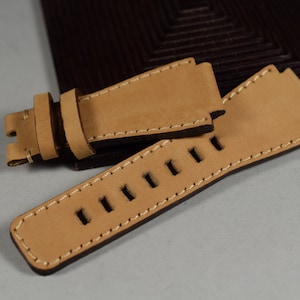 May include: Two tan leather watch straps with white stitching. One strap has a buckle and the other has holes for adjusting the size.