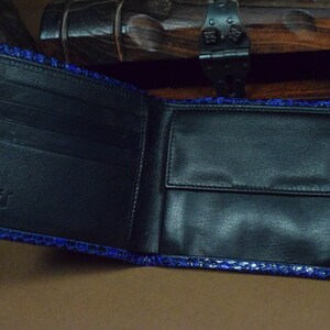 Peut inclure: Un portefeuille en cuir noir avec un motif de peau de serpent bleu. Le portefeuille comporte plusieurs compartiments et une fermeture &agrave; rabat.