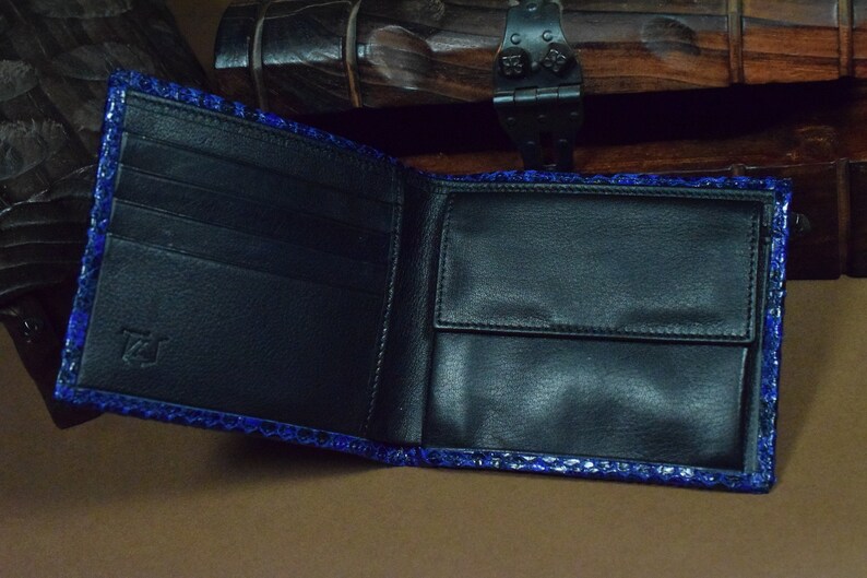 Peut inclure: Un portefeuille en cuir noir avec un motif de peau de serpent bleu. Le portefeuille comporte plusieurs compartiments et une fermeture &agrave; rabat.