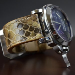 Könnte beinhalten: Eine silberne Uhr mit einem braunen Lederarmband. Das Zifferblatt der Uhr ist blau und trägt die Aufschrift "Luminor".