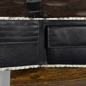 Pode incluir: Uma carteira de couro preto com v&aacute;rios slots para cart&otilde;es e um porta-notas. A carteira &eacute; feita de pele de pit&atilde;o genu&iacute;na com um padr&atilde;o branco e cinza.