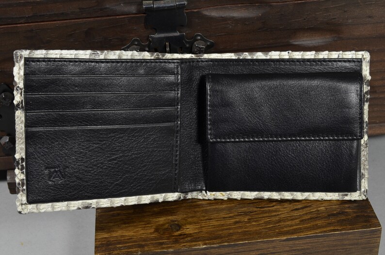 Pode incluir: Uma carteira de couro preto com v&aacute;rios slots para cart&otilde;es e um porta-notas. A carteira &eacute; feita de pele de pit&atilde;o genu&iacute;na com um padr&atilde;o branco e cinza.