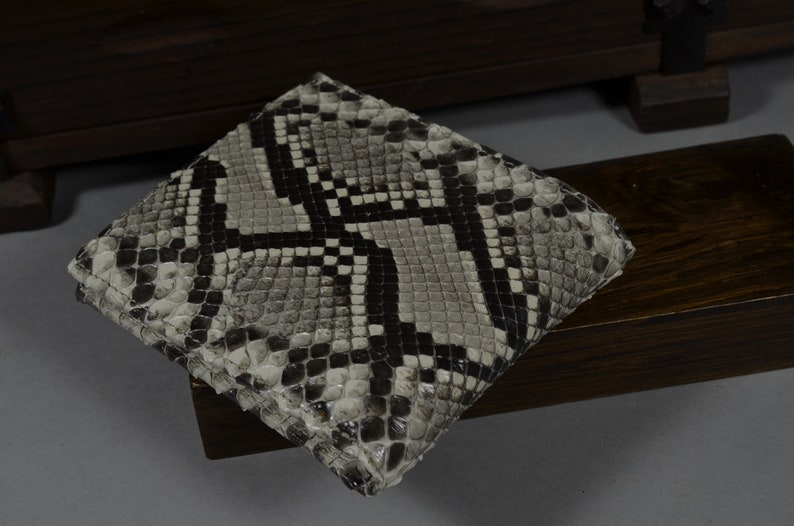 Pode incluir: Uma carteira de pele de cobra preta e branca com um padr&atilde;o texturizado.