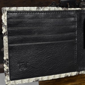 Pode incluir: Uma carteira de couro preta com v&aacute;rios slots para cart&otilde;es e um bolso separado. A carteira &eacute; feita de couro de cobra genu&iacute;no e tem um padr&atilde;o sutil.