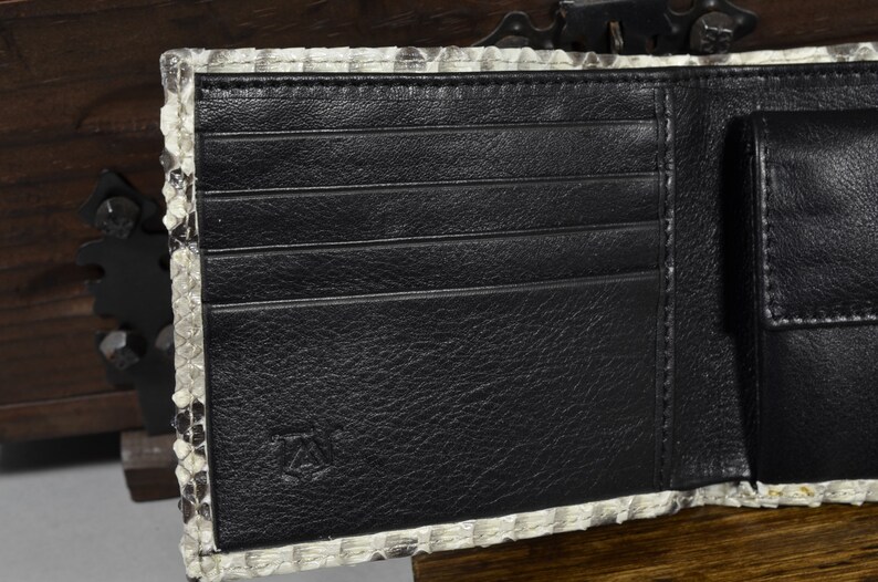 Pode incluir: Uma carteira de couro preta com v&aacute;rios slots para cart&otilde;es e um bolso separado. A carteira &eacute; feita de couro de cobra genu&iacute;no e tem um padr&atilde;o sutil.