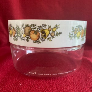 Puede incluir: Un tazón de vidrio transparente con un borde blanco y un diseño floral colorido con champiñones, limones y tomates. El tazón está etiquetado "PYREX® MADE IN U.S.A. not for freezer or rangetop use."