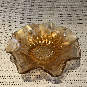 May include: A vintage amber glass bowl with a scalloped edge and a textured, raised pattern. The bowl has a starburst design in the center.