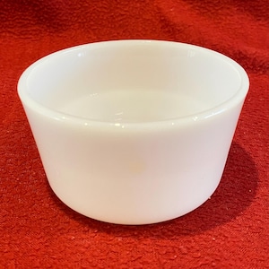 May include: A white ceramic bowl with a smooth, rounded rim. The bowl is empty and appears to be made of a thick, durable material.