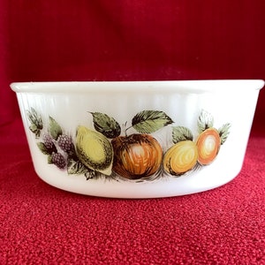 May include: White ceramic baking dish with a fruit design. The design features a red apple, yellow lemons, and green leaves.