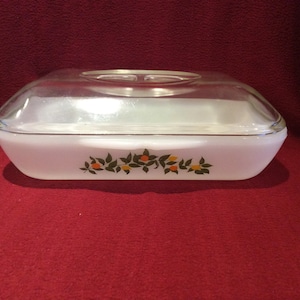 May include: White glass baking dish with a clear glass lid. The dish has a floral design with green leaves and orange fruit.