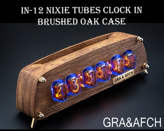May include: A wooden clock with a brushed oak case and a display of glowing orange Nixie tubes showing the time 23:55. The clock is made by GRA & AFCH.