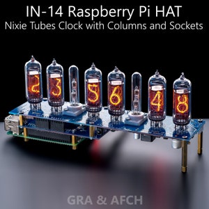 Puede incluir: Una placa de circuito azul con seis tubos Nixie naranjas que muestran los números 235648. La placa está etiquetada como "IN-14 Raspberry Pi HAT Nixie Tubes Clock with Columns and Sockets". La placa está montada en una superficie negra con una luz roja que brilla sobre ella.